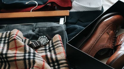 Una colección de ropa y accesorios para hombre, incluyendo un reloj, una bufanda a cuadros y zapatos de vestir.