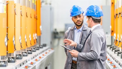 Ingenieros hablando mientras inspeccionan maquinaria.